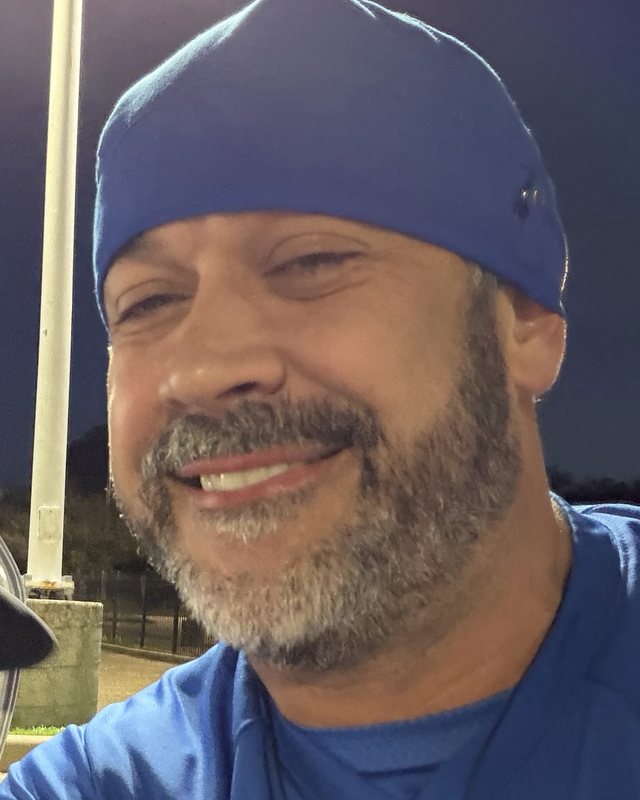 Chad Hurley, RN, smiling, in a blue scrub cap